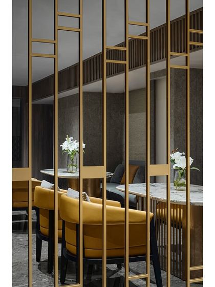 The mezzanine level at the Blue Sea Banquet, now a functional space for discussions or small gatherings. The design continues the theme of mirrored panels and metal jalis, with comfortable yellow armchairs adding a pop of color.