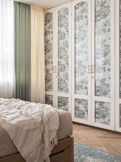We love adding unexpected details. In this bedroom, we designed the wardrobe with custom toile-patterned fabric panels, adding a touch of whimsy and tying into the room's French country theme.