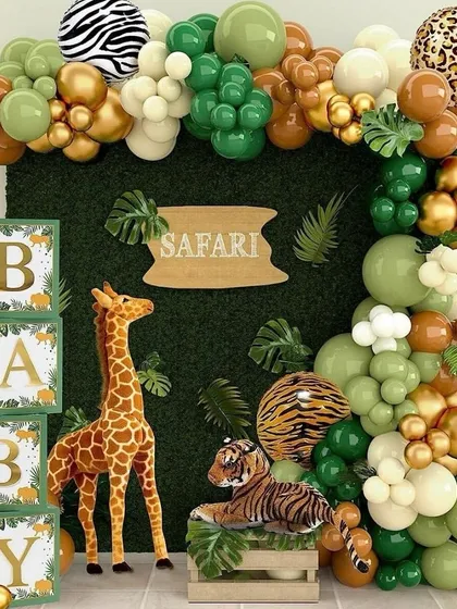 Let's go on an adventure with a Safari themed baby shower. This fun setup includes a boxwood hedge backdrop, a balloon garland in jungle tones of green, gold, and brown with animal prints, and cute props like a giraffe and tiger to bring the wild theme to life.