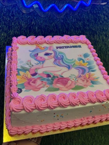 A simple yet sweet unicorn photo cake. The edible image is framed with a pink piped border, offering a budget-friendly way to bring the unicorn theme to your party.