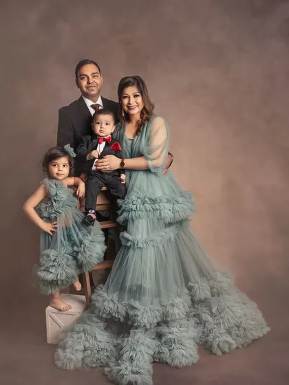 A formal family portrait with a touch of whimsy. The matching ruffled dresses for mom and daughter add a beautiful, coordinated element to this elegant family photo.