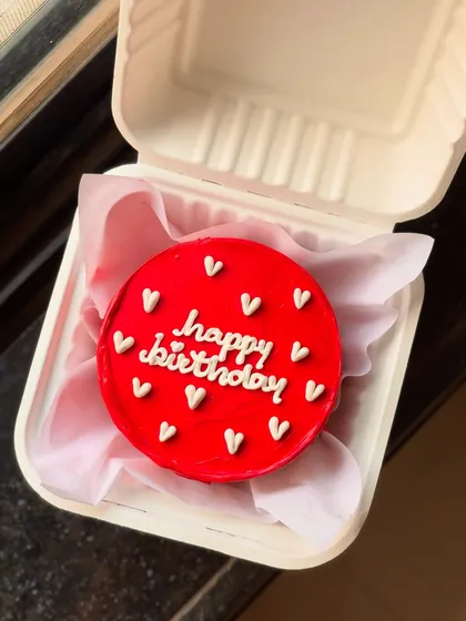 A bright red bento cake with "happy birthday" and tiny white hearts. It's a simple, classic, and cheerful way to celebrate.