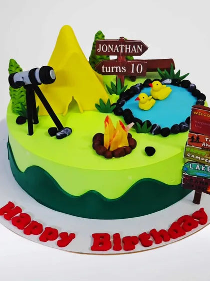 A camping-themed cake for an outdoor enthusiast. This design includes a tent, campfire, telescope for stargazing, and a small pond, capturing the spirit of adventure.