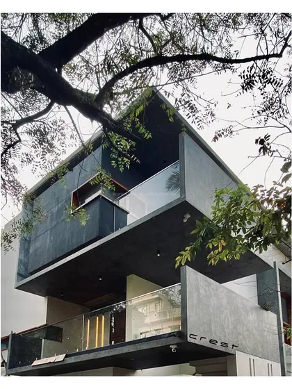 'Residence 97' nestled among the trees. This photo, taken during the finishing stages, shows the dark, textured facade and cantilevered balconies integrating with the surrounding urban foliage.