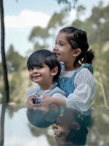 A sweet moment between siblings, with the older sister giving her brother a hug. The reflection adds a creative touch to this outdoor portrait.