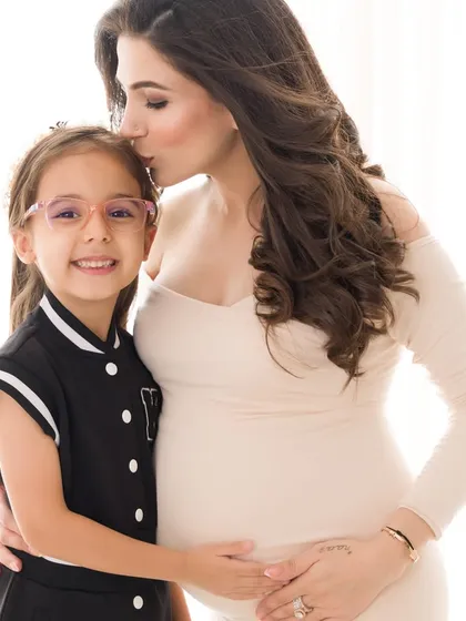 A gentle kiss for a loving big sister. This portrait is filled with the soft emotion and anticipation that a new baby brings to a family.