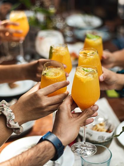 A group of friends raising their glasses in a toast, celebrating a moment together over a meal at our restaurant.