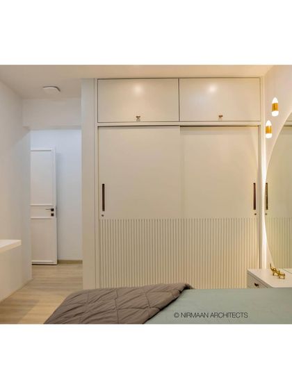 A master bedroom featuring a full-height upholstered headboard and integrated bedside tables. The design is seamless and sophisticated, with smart storage solutions built into the wardrobe.