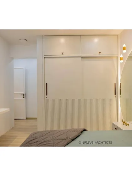 A master bedroom featuring a full-height upholstered headboard and integrated bedside tables. The design is seamless and sophisticated, with smart storage solutions built into the wardrobe.