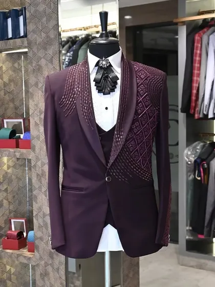 This deep purple three-piece tuxedo is designed for making a statement. The jacket features intricate, cascading beadwork on the shoulders and lapels, paired with a unique pleated bow tie.