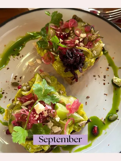 An artfully plated avocado toast from our September highlights. Topped with pickled onions, seeds, and a drizzle of green oil, it's a gourmet take on a classic favorite.