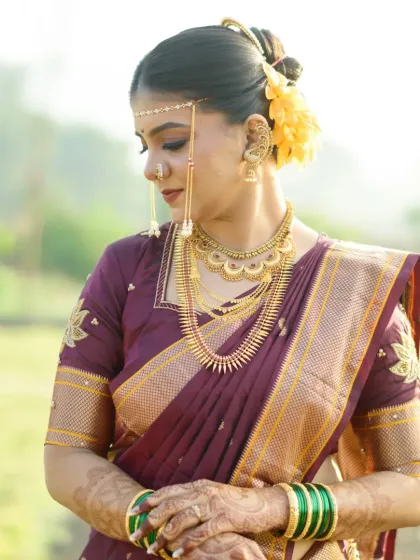 A traditional bridal portrait featuring classic gold jewellery, a mundavalya, and a beautiful wine-colored saree.