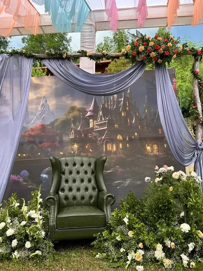 A whimsical photo corner for a Mehendi, featuring a fantasy castle backdrop and a vintage green leather armchair, creating a magical, storybook feel.