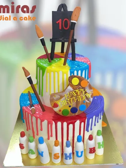 A masterpiece for a budding artist. This vibrant two-tier cake uses a rainbow drip effect to mimic flowing paint, complete with an edible artist's palette, brushes, and an easel, turning a birthday into a colorful work of art.