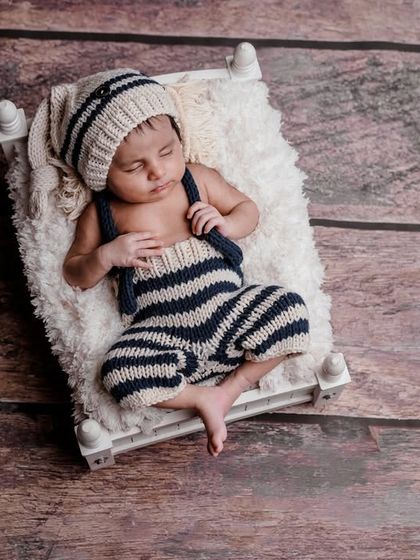 A tiny sailor dreaming of the sea. This setup uses a rustic wooden floor and a cute, knitted nautical outfit for a charming and timeless photo.