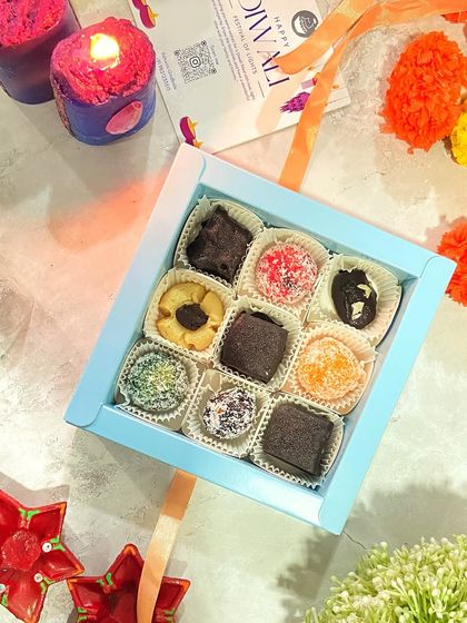 An assortment of my bite-sized Diwali treats, including coconut laddus, nutty cookies, and rich chocolate bites, all arranged in a beautiful blue gift box.
