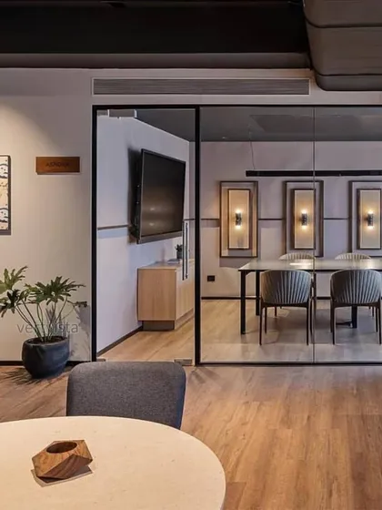 A wider perspective of how a single, well-placed plant can enhance an entire office space. The potted Philodendron adds a natural, sculptural element to the lounge area, complementing the modern and minimalist interior design.