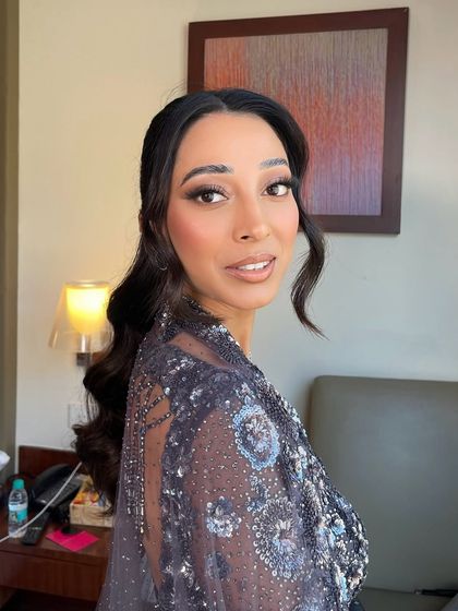 A beautiful portrait of a client with a wavy ponytail. The front sections are left soft and wavy to frame the face.