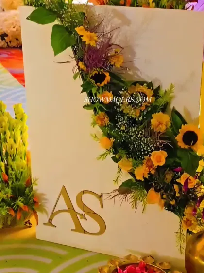 A custom monogram sign adorned with a cascade of sunflowers and other yellow blooms.