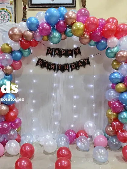 A clear, centered view of the colorful chrome balloon arch with a fairy light curtain, ideal for a photo backdrop.