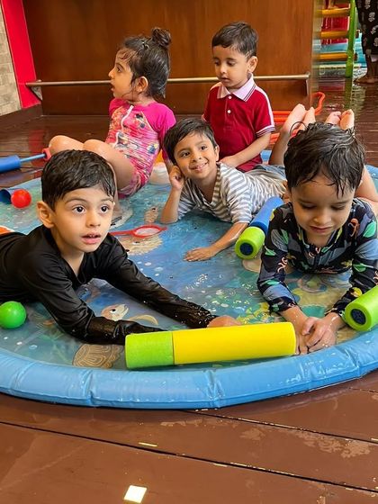 A moment of calm amidst the fun. The kids are enjoying the water play area with their friends during our special Holi session.