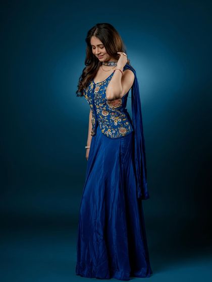 This pose highlights the graceful silhouette of the outfit and the unique one-sided drape attached to the jacket.