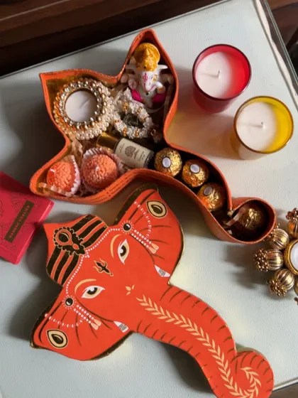 My Ganesh Chaturthi collection is all about unique and thoughtful designs. This special Ganesha-shaped box is filled with laddoos, Ferrero Rocher chocolates, a mini Ganesha idol, and a beautiful pearl-studded candle holder.