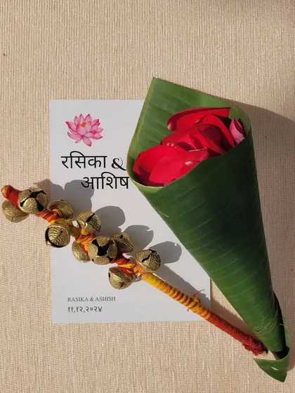 Personalized wedding stationery paired with traditional elements like ghungroos and a cone of rose petals for showering the couple.
