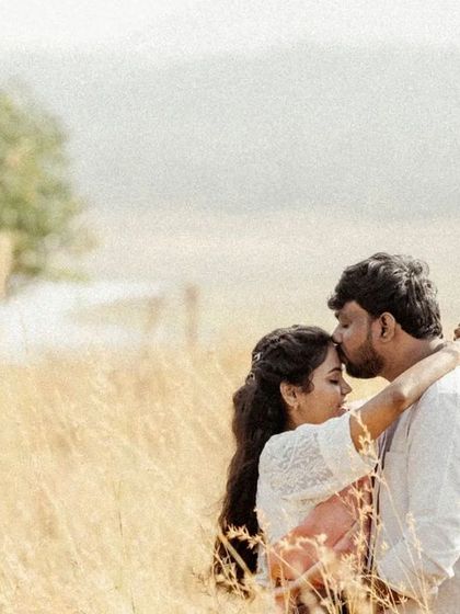 A gentle and romantic portrait of a forehead kiss in a golden field, capturing a moment of pure affection.