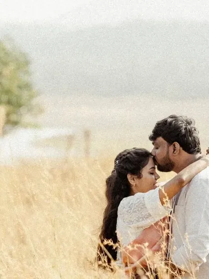 A gentle and romantic portrait of a forehead kiss in a golden field, capturing a moment of pure affection.