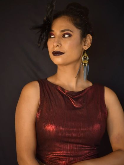 The side profile highlights the dramatic eye makeup and the unique feather earring, completing the artistic look.