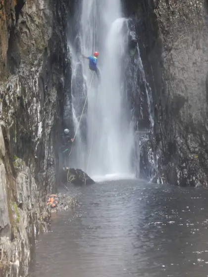 A different angle of the Knotty Canyon rappel, showing the challenging rock formations and powerful water flow.