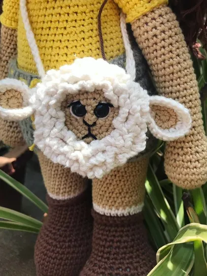 This is a special little lamb bag I created. It's a functional accessory, perfect for carrying small items, and also a unique piece of wearable art. The fluffy texture of the lamb's wool is created with a special loop stitch.