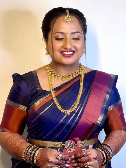 Bride Supritha's look for her Varpooja ceremony. She is dressed in a stunning royal blue silk saree, and her makeup is kept traditional and elegant with a bold red lip.