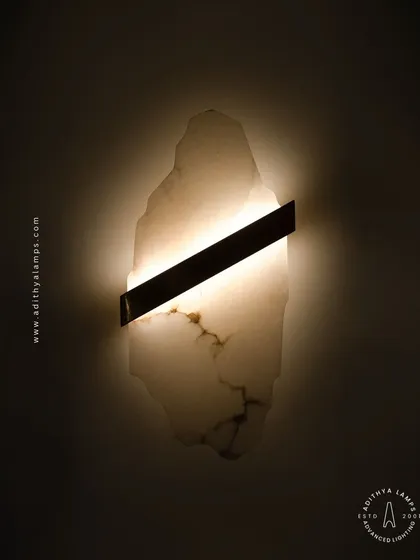 This unique wall sconce celebrates the raw beauty of natural materials. A slice of rustic, translucent marble is bisected by a sleek metal band, creating a warm, diffused glow that highlights the stone's organic patterns. A perfect piece of wall art and lighting in one.