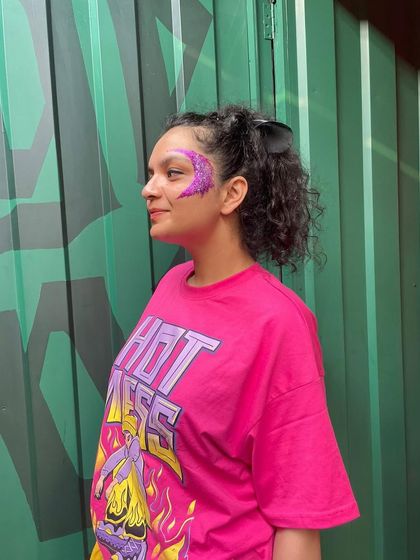 Another angle of the vibrant purple glitter face art. It shows how the design catches the light and accentuates the face.