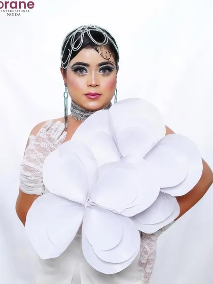 The use of a large, paper flower as a prop adds a surreal and artistic element to the shoot.