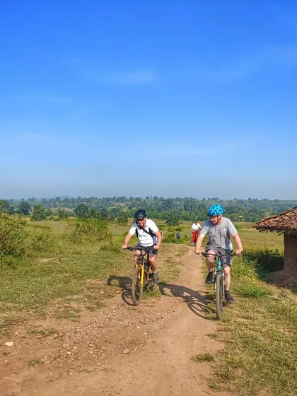 Two cyclists ride past a traditional mud house on a village path near Kanha. This tour is a journey back in time, exploring the simple and sustainable lifestyle of the local tribes.