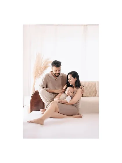 A tender moment between new parents and their baby. The soft lighting and neutral colors of the studio create a serene atmosphere for this beautiful family portrait.