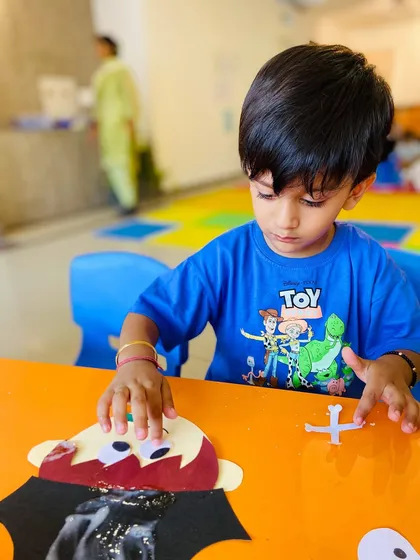 A student works on a vampire craft, showing how we incorporate seasonal themes like Halloween into our activities.