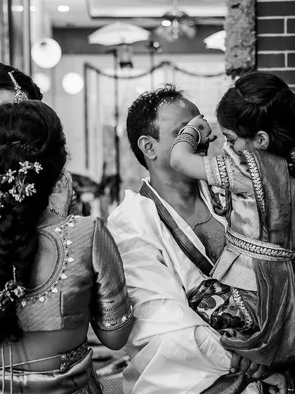 A tender, candid black and white moment of a child touching her father's face during a ceremony. These unscripted interactions are the heart of our documentary photography style, capturing pure love.