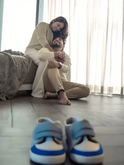 The tiny shoes in the foreground hint at the little feet that will soon fill them. This creative shot beautifully frames the couple in the background, telling a story of anticipation.