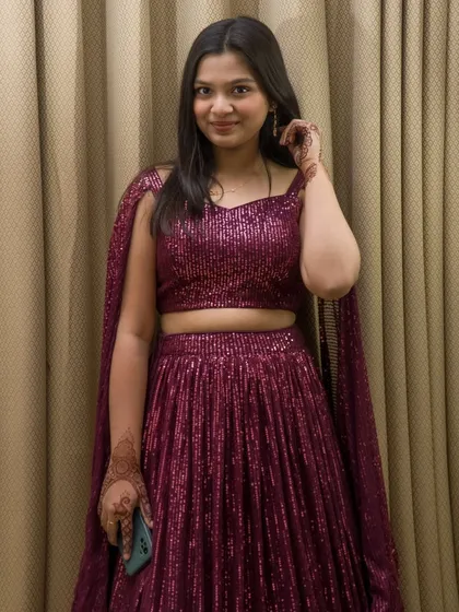 A full-length view of the sequined lehenga, showing the complete outfit. The model is holding a phone, adding a modern, casual touch.