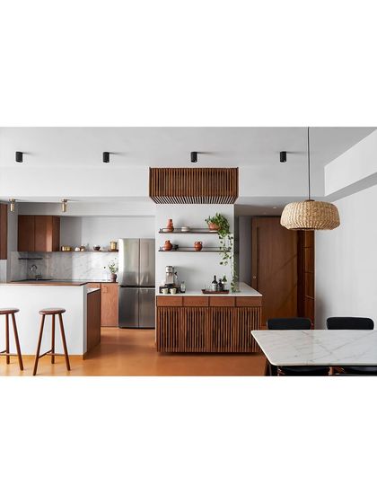 An open-plan kitchen and dining area featuring custom wood cabinetry. The slatted wood details on the island and overhead unit add a strong textural element and demonstrate my focus on detailed woodworking.