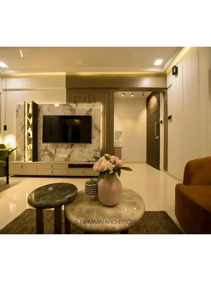 A modern classic living room with a marble TV unit that includes display niches. The design balances the visual weight of the television with elegant storage and decor elements.