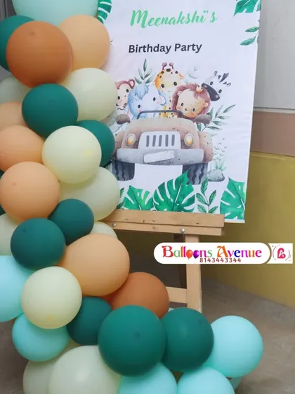 A personalized welcome sign for Meenakshi's jungle-themed birthday party. The sign is placed on an easel and decorated with a matching balloon garland.