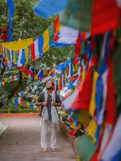 Standing amidst a sea of colorful Tibetan prayer flags in Darjeeling. The composition uses the flags to frame the shot, creating a vibrant image that speaks of peace and spirituality.