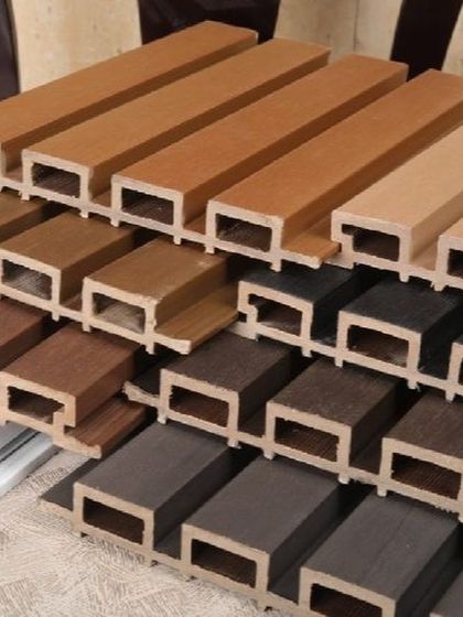 A collection of our WPC louver samples stacked to show the different colors and wood grain finishes we have in stock.