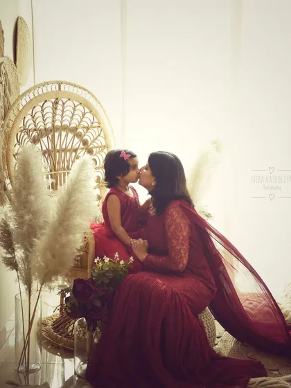 A kiss between mother and daughter. This silhouette-style shot is artistic and full of emotion, beautifully capturing a tender moment in a boho-chic setting.