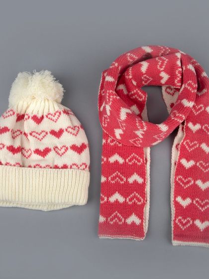 A kids' winter beanie and scarf set with a pink and white heart pattern.